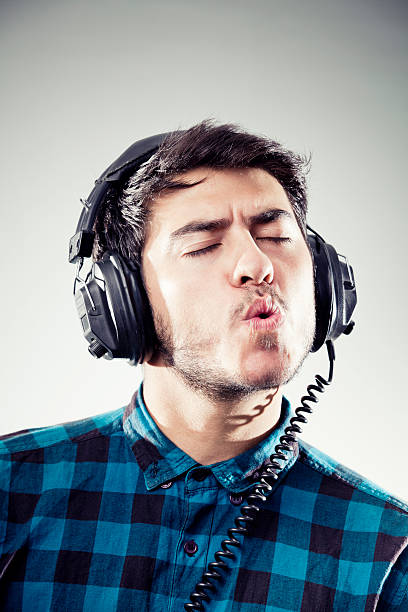 High contrast diffused portrait of a young boy wearing a pair of headphones and shouting.You can find more photographs of this model in