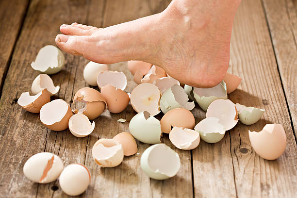 Walking On Eggshells A close up shot of a barefoot walker about to step on some cracked eggshells. Concept shot for walking on eggshells. animal egg walking on eggshells walking broken stock pictures, royalty-free photos & images