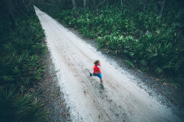 istock Solitary male runs under trees on road at sunset 175515887