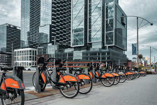 Bikes are standing in a row at a bike sharing station in downtown Toronto, Ontario, Canada on a cloudy day.
