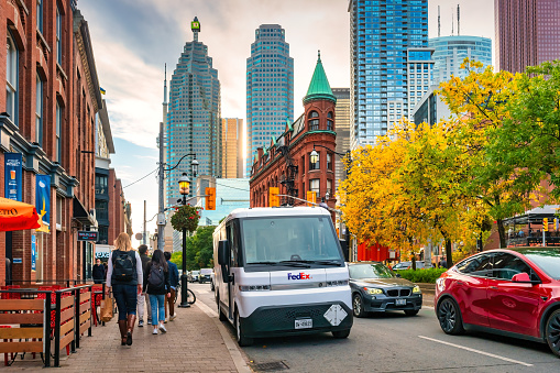Pedestrians walk past a Zevo 600 electric delivery van in downtown Toronto, Ontario, Canada on a sunny day.
