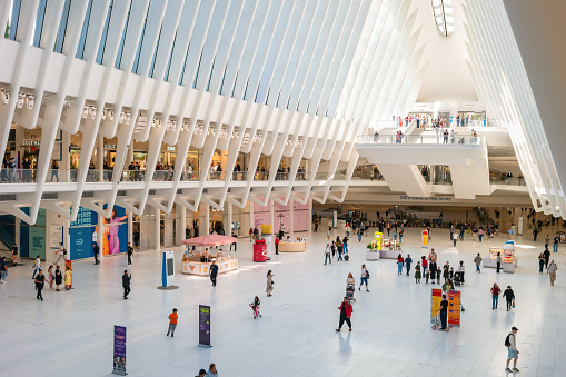 People walk inside the Oculus Center transportation hub and shopping mall in New York City, USA on a sunny day.