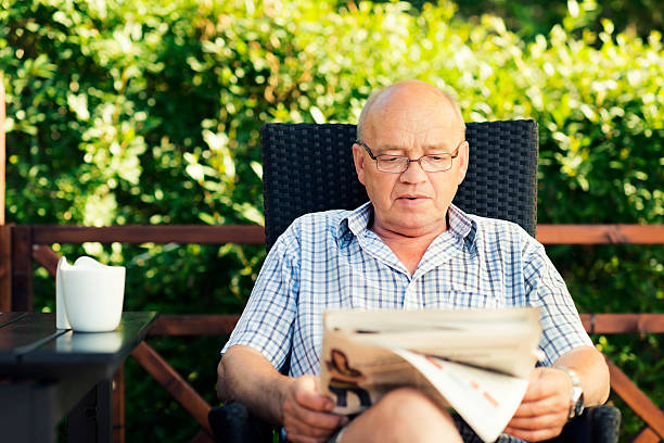 istock Senior man in garden reading a newspaper beside table 175516719