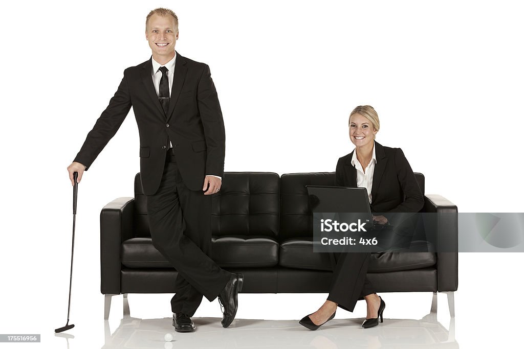 Uomo d'affari in piedi con una mazza da golf e una donna d'affari - Foto stock royalty-free di Abbigliamento elegante