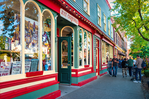 People walk past colorful stores in Niagara on the Lake, Ontario, Canada on a sunny day.