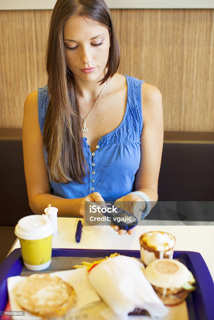 Adolescente haciendo prueba de azúcar en la sangre en un restaurante. - Foto de stock de Actividad libre de derechos