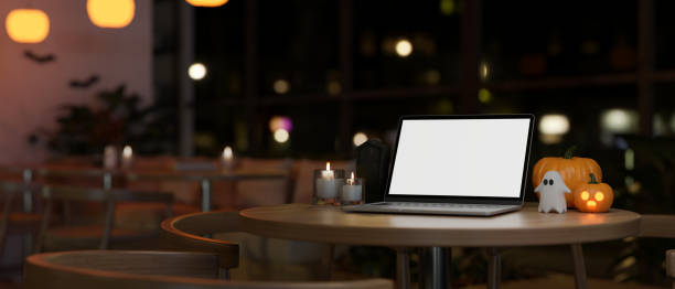 istock Workspace in Halloween theme with a white-screen laptop mockup on a table in a cafe at night. 1755190862