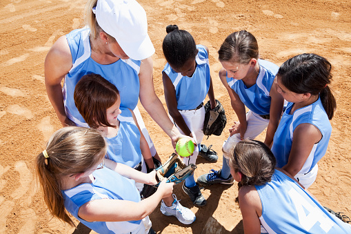 Girls softball team meeting in huddle on infield.
