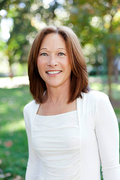 istock middle aged woman smiling, wearing white  175519621