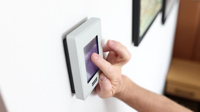 Closeup of man hand adjusting modern wall mounted digital thermostat