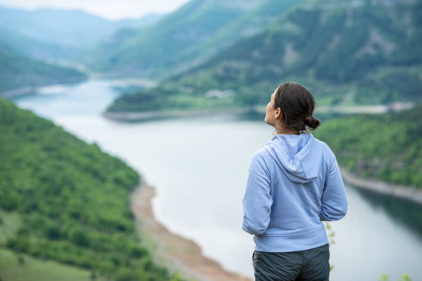 istock Woman looks at lake from high viewpoint in spring. 1755198653