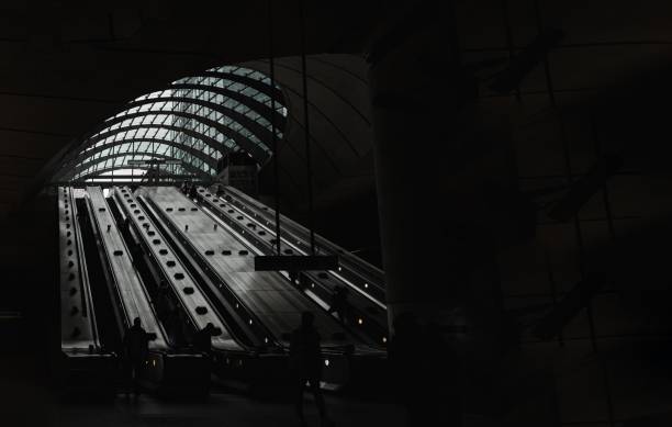 personas subiendo por las escaleras mecánicas dentro de la estación de metro de canary wharf. - people metal sign way out sign fotografías e imágenes de stock