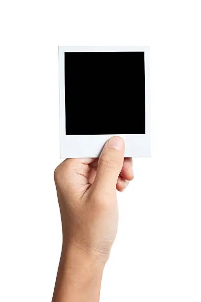 "A hand holding blank instant photo, isolated on white background. Clipping path included."