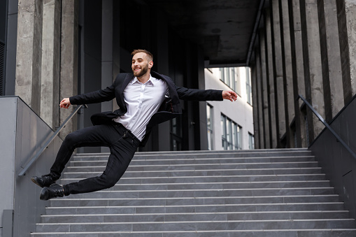A businessman jumping at the top of stairs