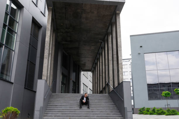 istock Concepts of work problems and personal issues beset : Business man sitting and feeling stressed and depressed on the stairs of a corridor on unfavorable weather 1755206323
