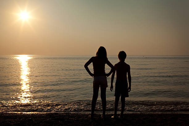 istock Silhouette of Two Children Watching Sunset Over Beach 175520656