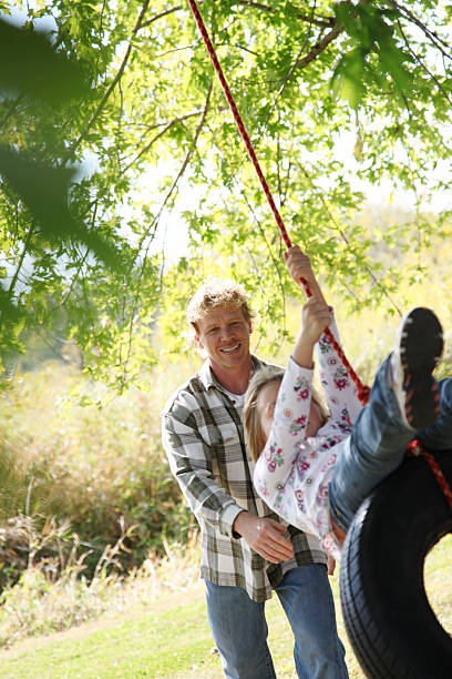 istock father pushing daughter on tire swing 175521085
