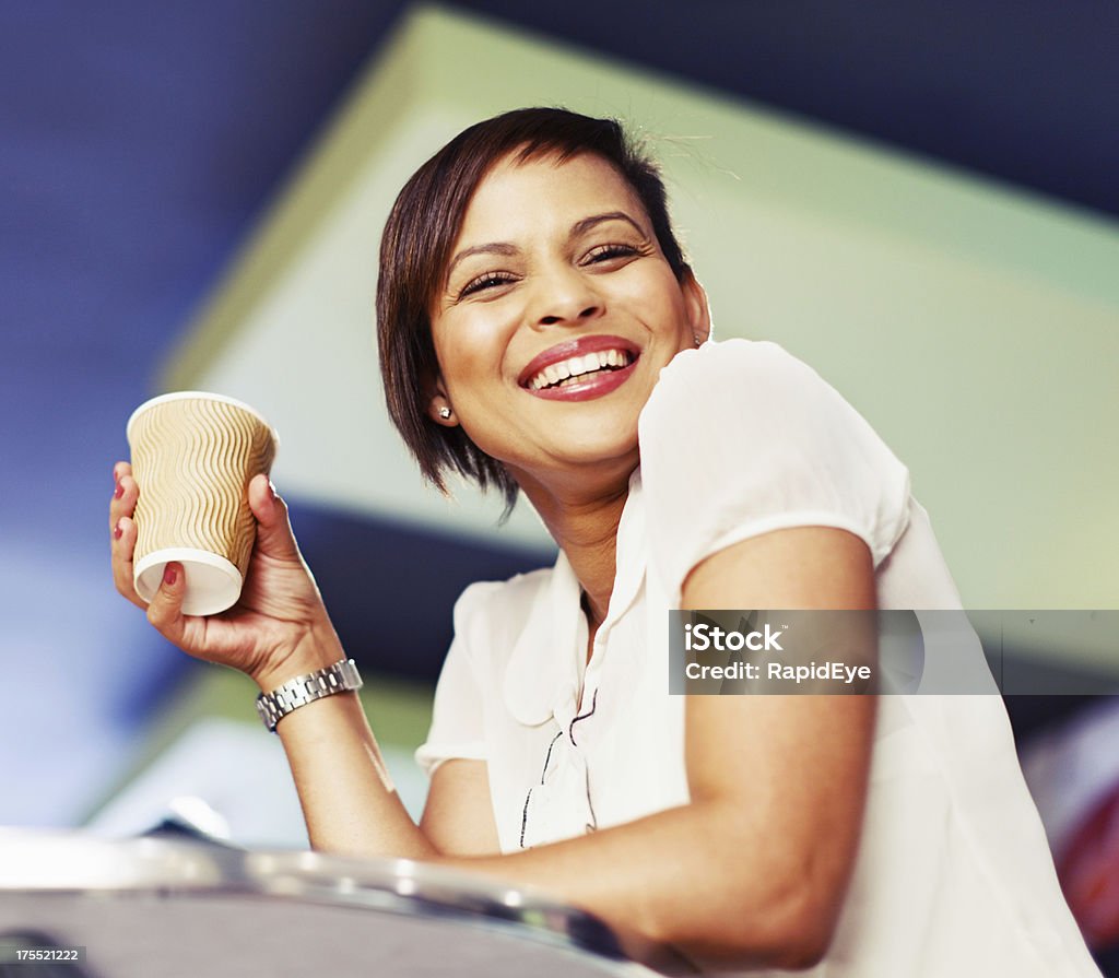 Beautiful smiling young woman with coffee in cafe "A beautiful golden-skinned young woman looks at camera, smiling flirtatiously, as she sits in a supermarket's in-store cafe. Focus is on her face." 20-29 Years Stock Photo