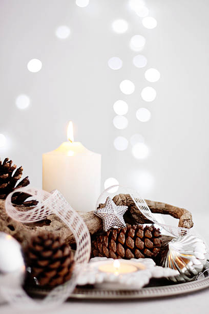 Christmas centerpiece with candles, pine cones, branch and silver decor stock photo