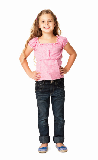 Full length portrait of a cute little girl smiling with hands on hip. Vertical shot. Isolated on white.