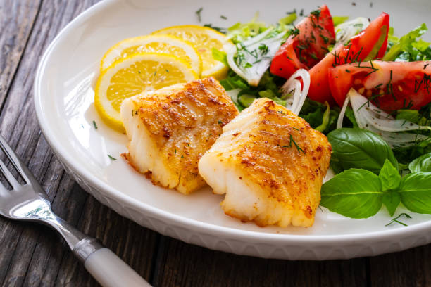 istock Fried cod fillet and fresh vegetables on wooden table 1755217463