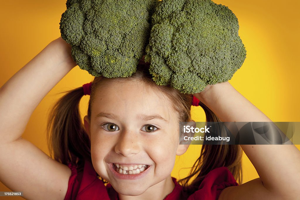 Счастливый Маленькая девочка держит брокколи на ее голову - Стоковые фото 6-7 лет роялти-фри