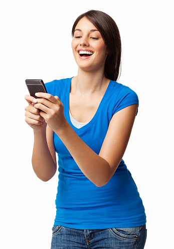 Happy young woman in casual wear reading text message on cell phone. Vertical shot. Isolated on white.