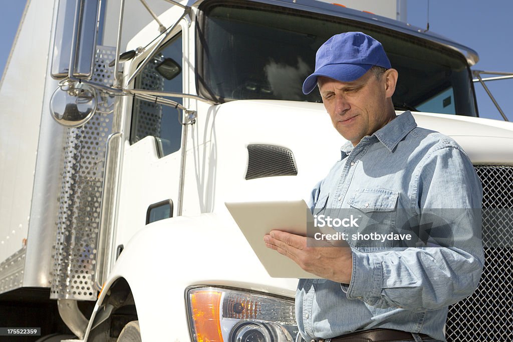 Computer Tablet and Trucker An image from the transportation industry of a truck driver using his computer tablet PC while leaning against his truck. Truck Driver Stock Photo