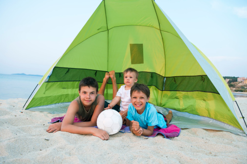 Cute boys  enjoying under tent at the beach