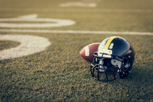 An American football helmet and football on the football field. Perfect image for your football announcement.