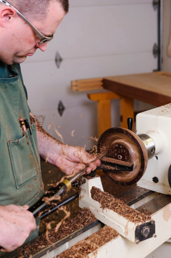A woodworker carving a bowl on a lathe in his shop.
