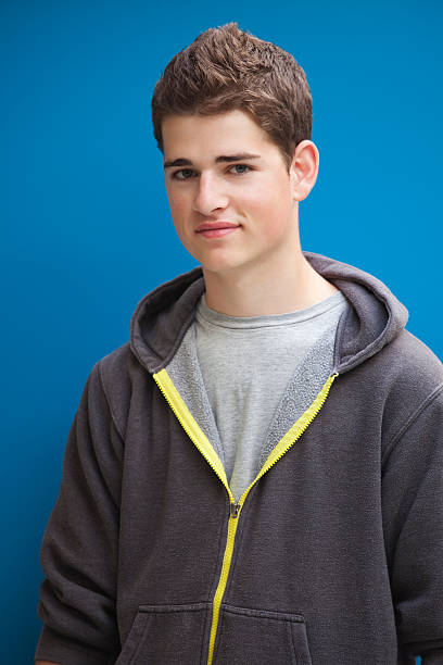 High School Student Handsome teenager standing in front of a blue background. high school photos stock pictures, royalty-free photos & images