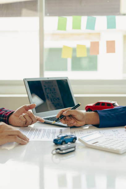 istock A friendly car salesman is sitting at a table with a customer. and provide the customer with a properly signed purchase contract in the name of successful vehicle sales, vertical close-up view. 1755246349