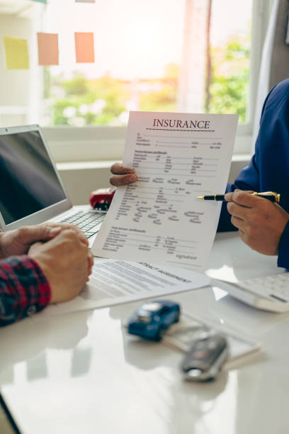 istock A friendly car salesman is sitting at a table with a customer. and provide the customer with a properly signed purchase contract in the name of successful vehicle sales, vertical close-up view. 1755246651