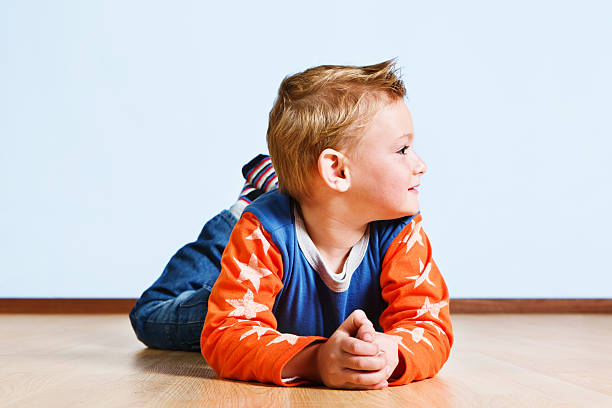 istock Smiling pre-schooler lies on floor, playing 175525122