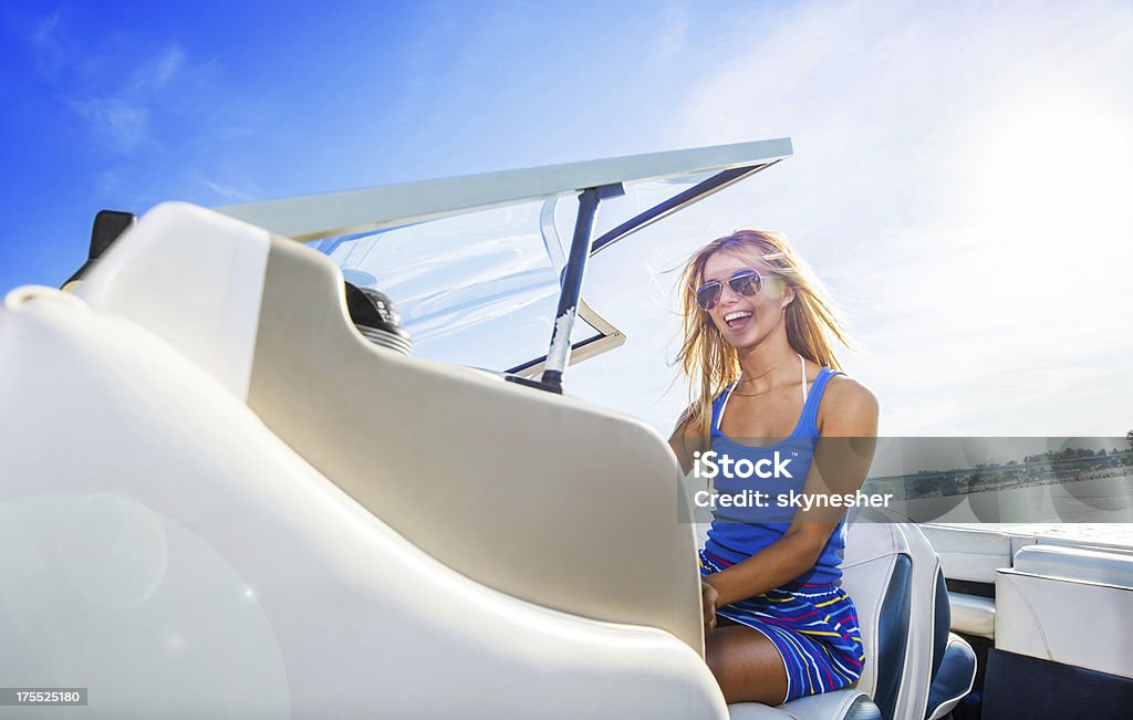 Beautiful young blonde woman riding a speedboat. Cheerful blonde teenage girl riding a speedboat against the blue sky. Adolescence Stock Photo Beautiful young blonde woman riding a speedboat. Cheerful blonde teenage girl riding a speedboat against the blue sky. Adolescence Stock Photo