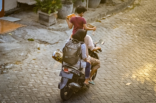 a family consisting of both parents and children riding on a motorbike. His son was seen standing on the motorbike seat, Indonesia, 19 October 2023.