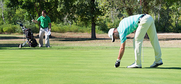 golfspieler und caddy auf das putting green - golf golf course putting green hole stock-fotos und bilder