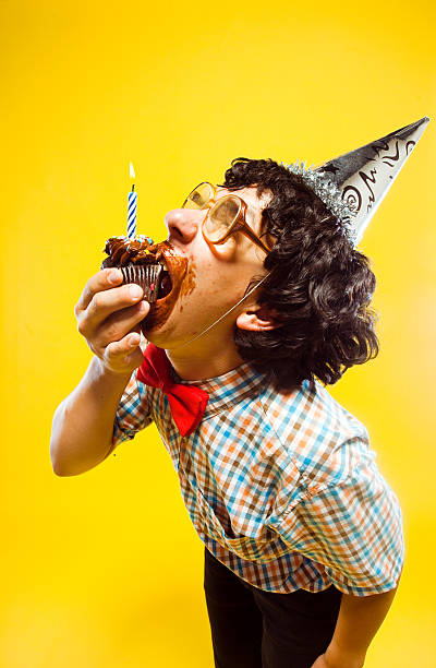 istock Messy Frosting Eating Birthday Boy Nerd Takes Bite from Cupcake 175526393