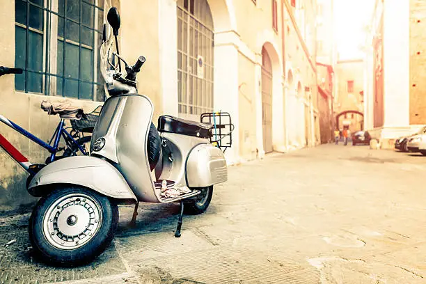 Vespa scooter in an old street of Siena (Tuscany, Italy).