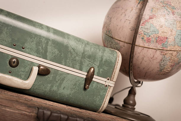 Retro Green Suitcase and Globe Sitting on Wood Trunk
