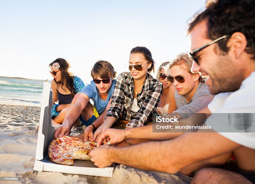 Giovani che godono di una festa in spiaggia - Foto stock royalty-free di Pizza