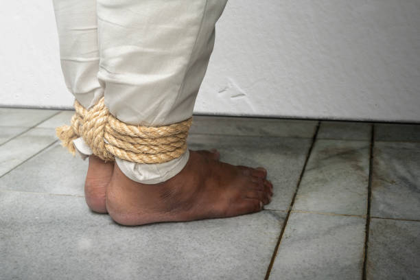 The man's legs are tied by rope