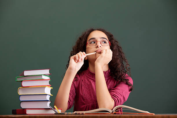 istock Little girl sitting and thinking before blackboard 175529286