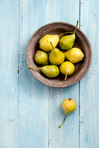 Fresh pears in a bowl on wooden table