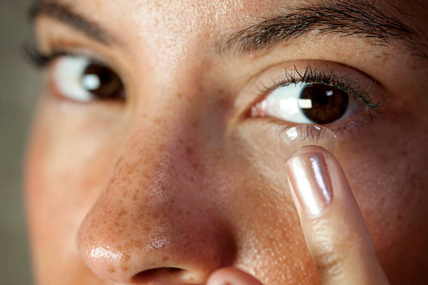 Inserting contact lens Eye contact from a pretty young mixed race woman inserting a contact lens into her eye.  Macro focus on the lens and eyelash. contact lens stock pictures, royalty-free photos & images