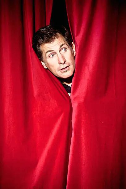 Actor peeking through a curtain.More of this theme: