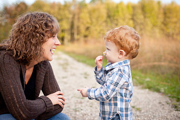 Mother Smiling at Little Son Smelling Wildflower