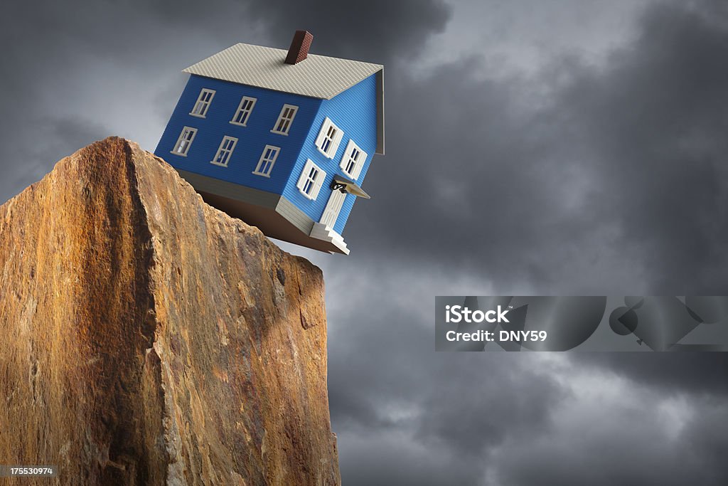 Housing Crisis A house teetering on the edge of a cliff with stormy skies in the background.To see more of my financial images click on the link below: Cliff Stock Photo