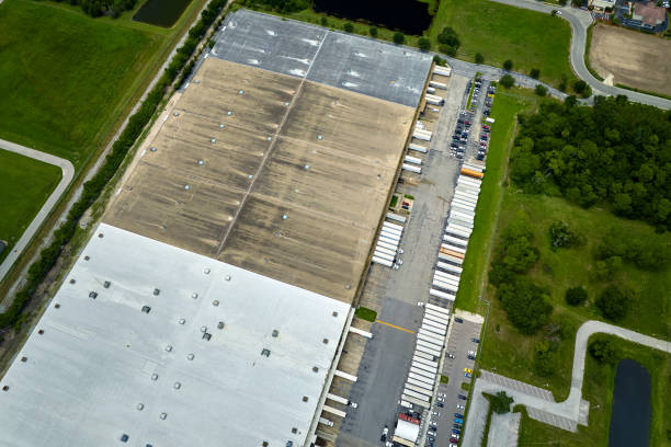 istock Aerial view of large commercial loading bay with many delivery trucks unloading and uploading retail goods for nationwide distribution. Global economy concept 1755314298